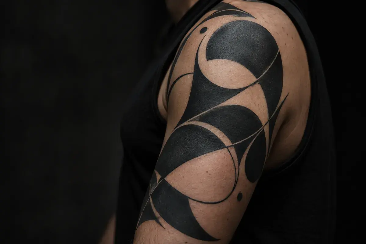 An illustrative healed abstract blackwork tattoo on an adult upper arm